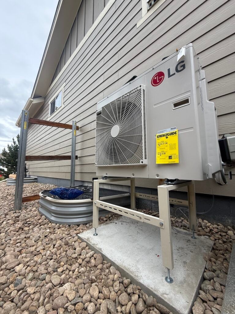The new LG RED heat pump elevated and sitting on solid concrete on the side of his home.