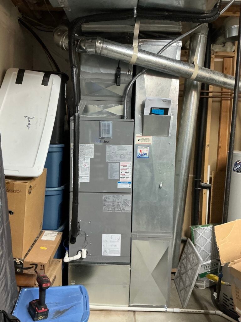 New Midea air handler installed in Robert Germain's basement mechanical room, connected to the existing sheet-metal ductwork.