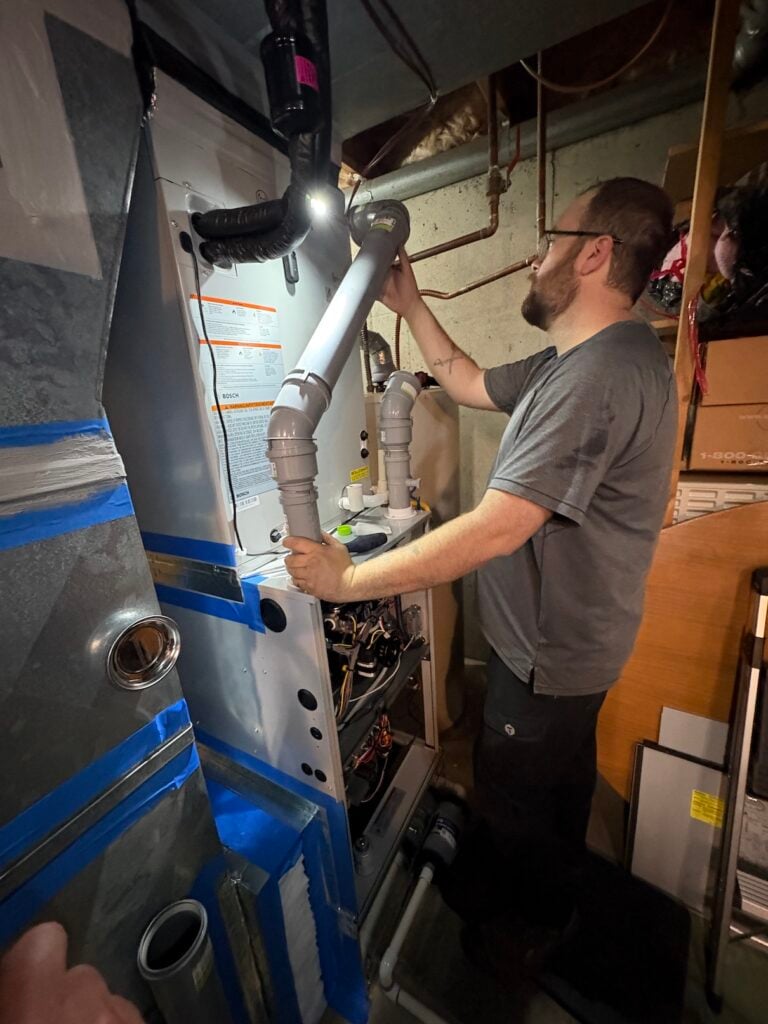 A JHP installer connecting PVC venting to the new Bosch dual-fuel furnace in David's basement during the install.