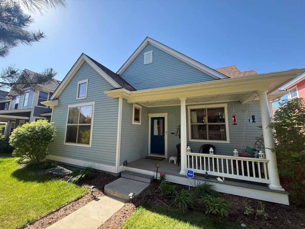 Front exterior of Robert Germain's light-blue craftsman-style home with covered porch before the heat pump installation.
