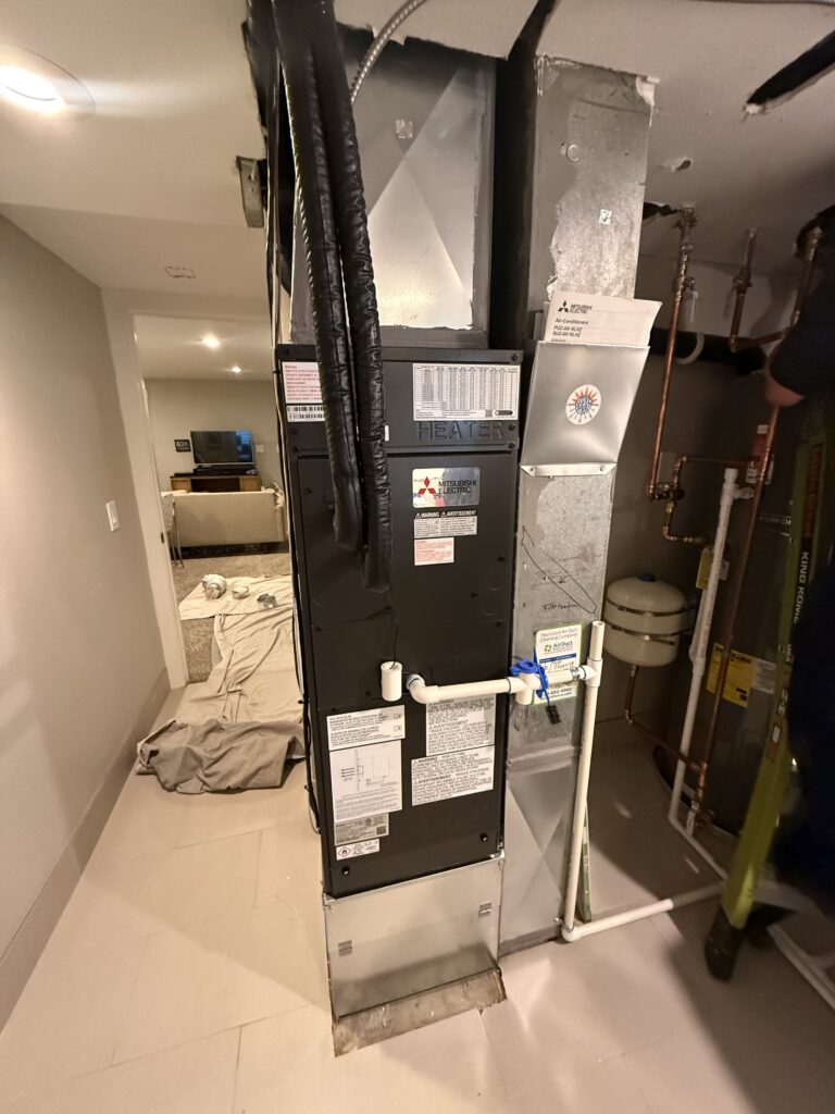 New Mitsubishi Electric heat pump air handler installed in a Denver basement utility area after replacing the gas furnace