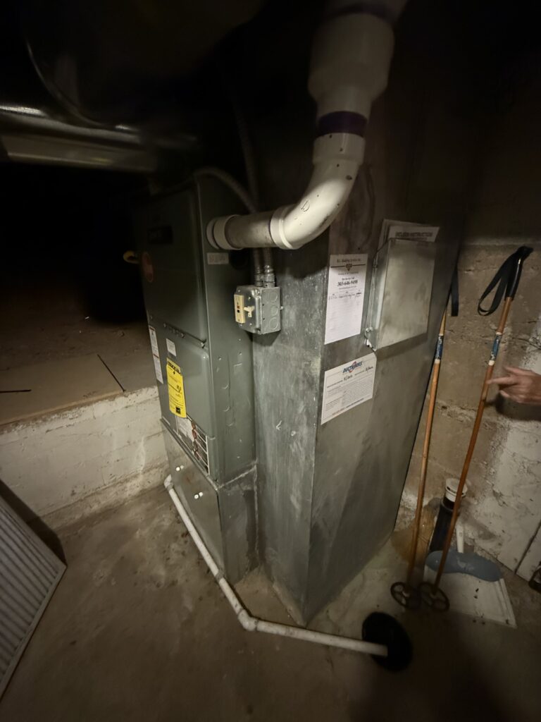 Old gas furnace with flue piping in a basement before heat pump replacement