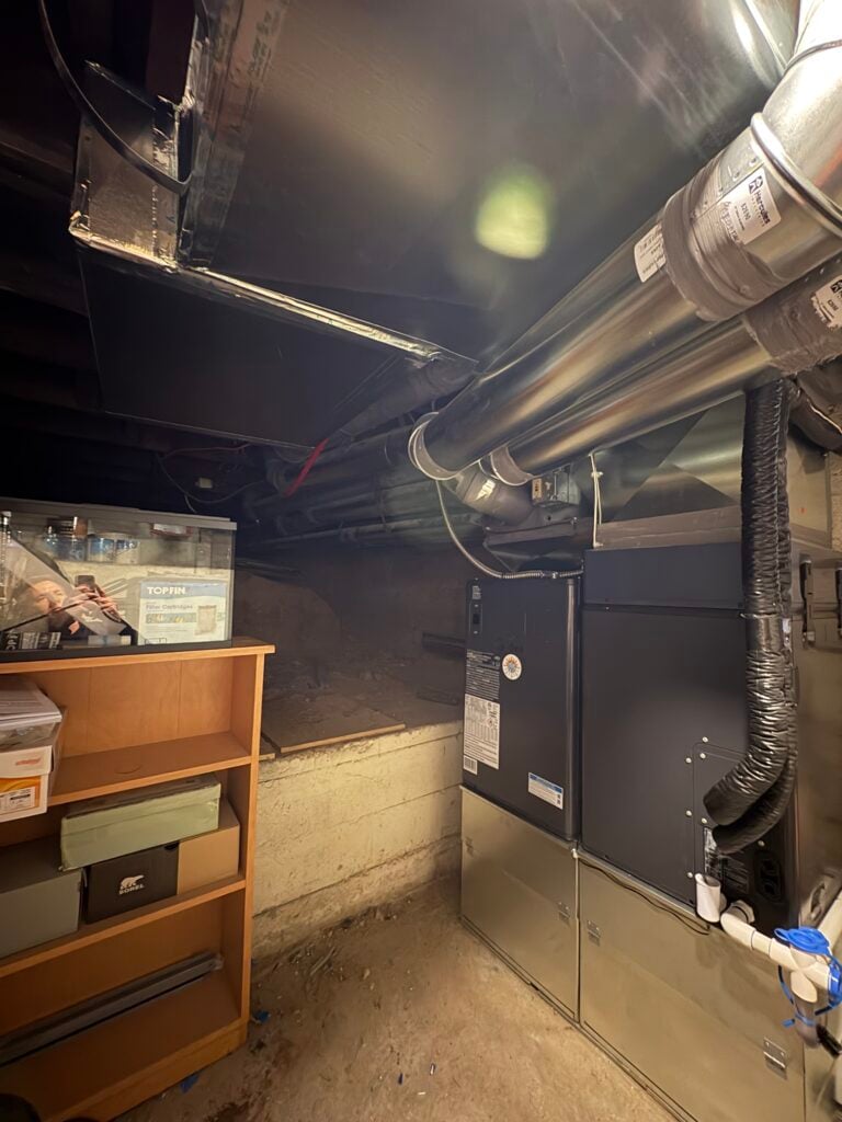 New heat pump air handler and ductwork installed in a basement utility area