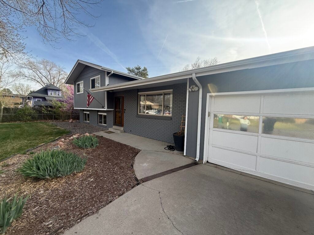 Front exterior of a gray split-level brick home before heat pump installation