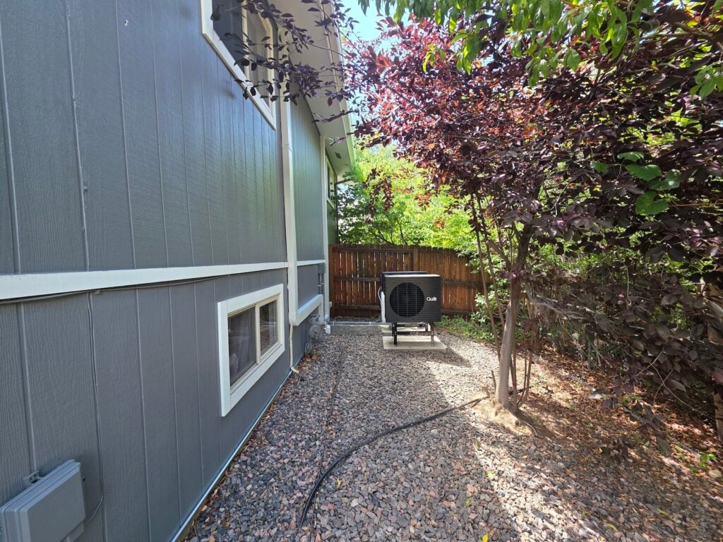 Quilt outdoor heat pump unit installed along the side of a Denver-area hom