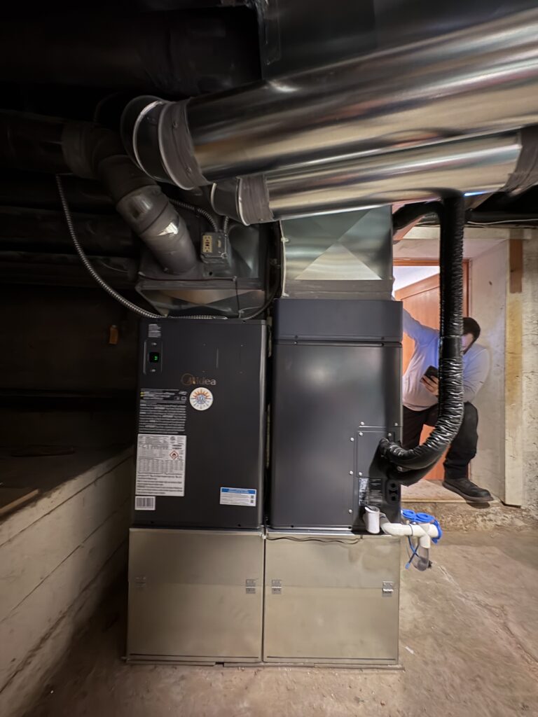 Close-up of a new Midea heat pump air handler installed in a basement