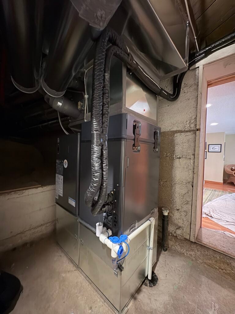 New Midea indoor air handler connected to ductwork in a basement after heat pump installation