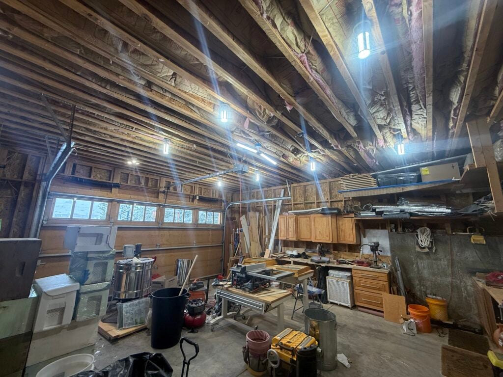 Interior of a converted garage workshop with exposed framing before heat pump installation in Lone Tree, CO