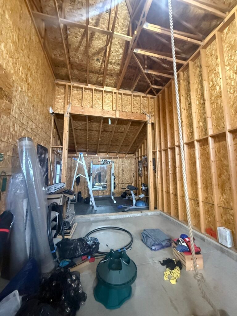 Unconditioned converted garage space with exposed framing and a home gym before heat pump installation in Lone Tree, CO