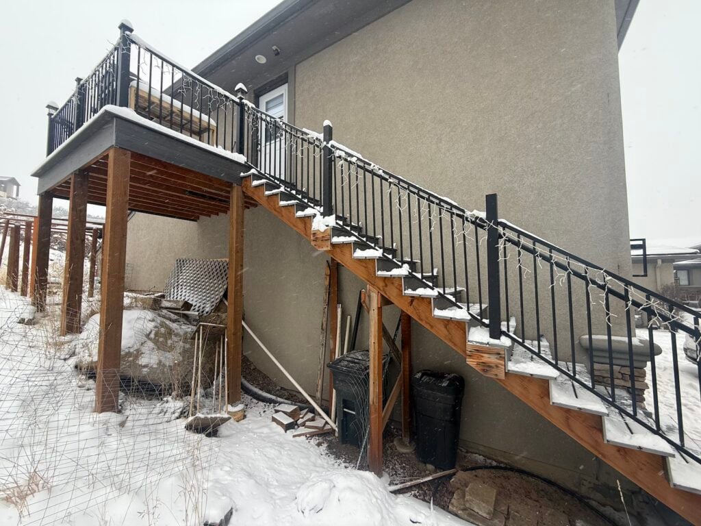 Exterior of a Lone Tree, CO home with a raised deck and stairs in the snow before the outdoor heat pump condenser install