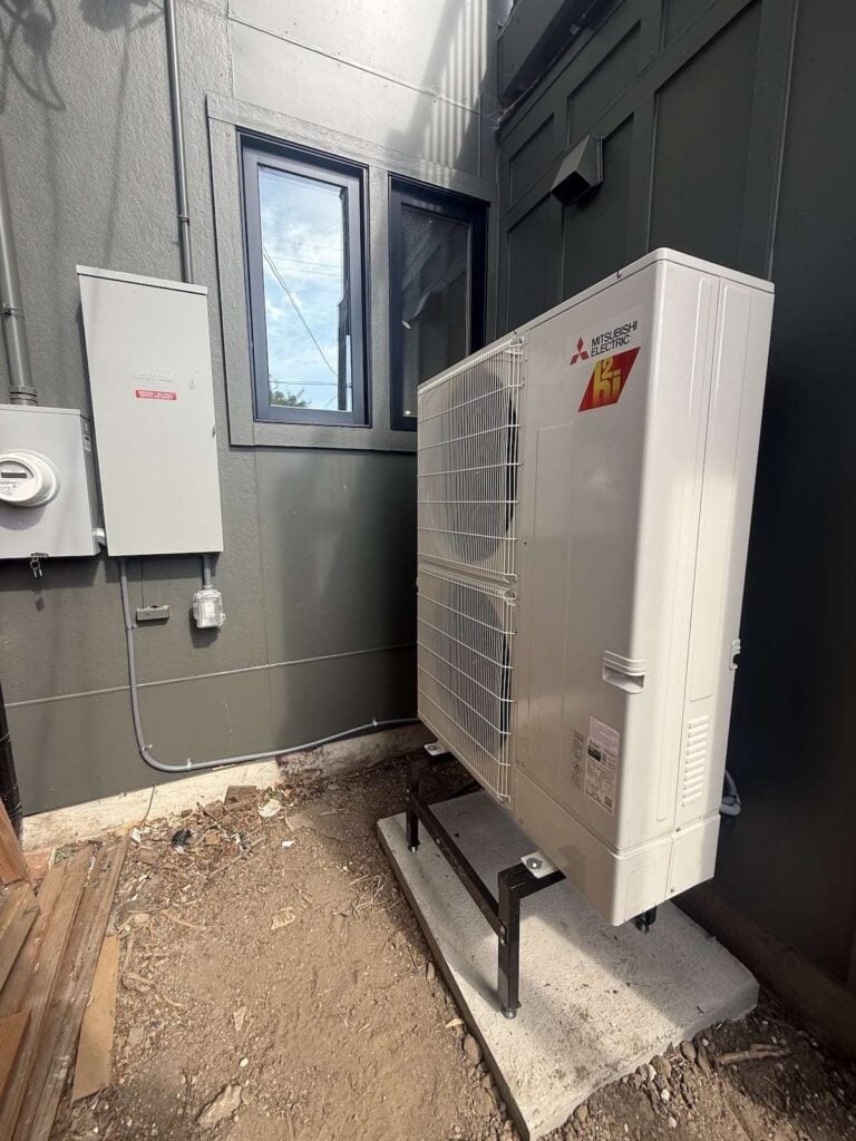 One of our Denver, CO Mitsubishi heat pump installations outside a new whole-home renovation elevated on a concrete pad