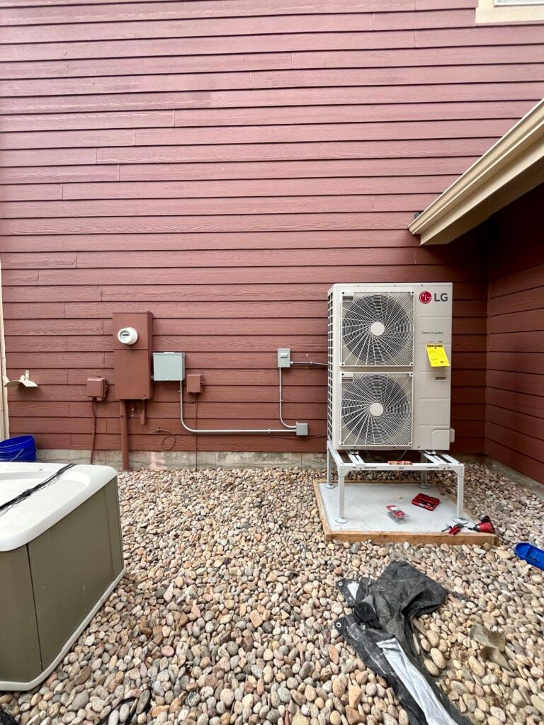 Our 3.5 Ton LG RED heat pump installed and elevated on a concrete stand next to the home of our Aurora CO customer's house.