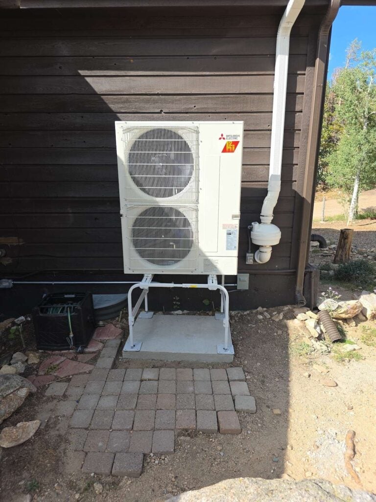 A Mitsubishi heat pump installed at a Golden, CO home surrounded by trees and up in the mountains